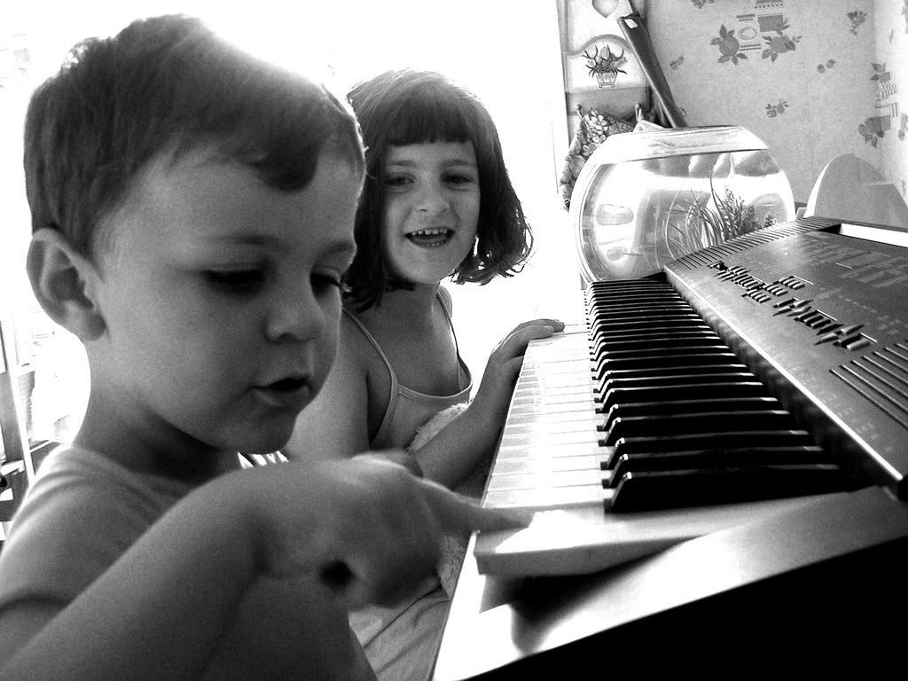 Niños pequeños divirtiéndose con un piano